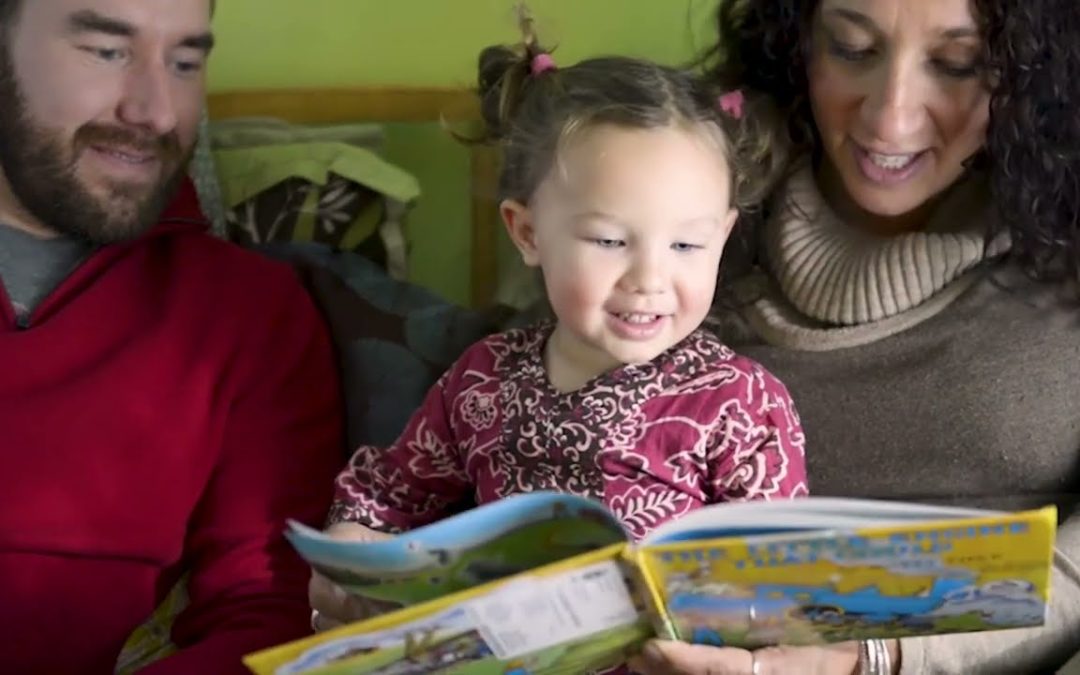 A family reading a book with their Daughter.