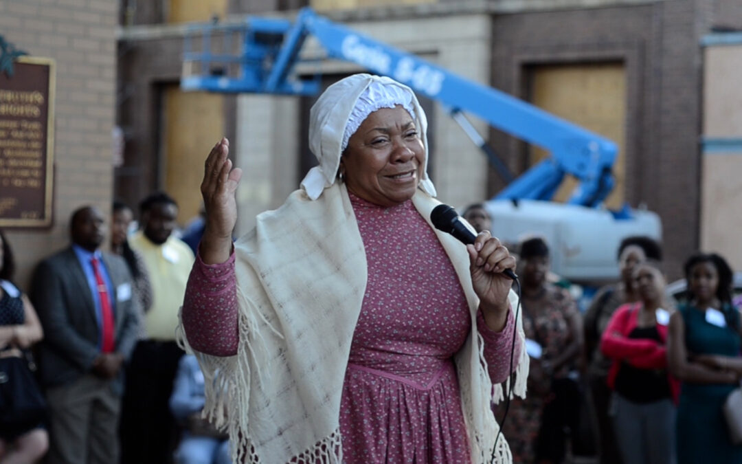 A woman speaking into a microphone at Sojourner Truth Legacy Plaza